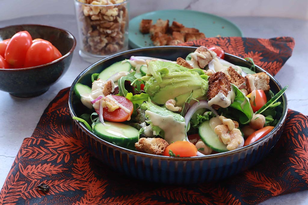 Insalata vegana con rosa di avocado, ceci e dressing di tahini